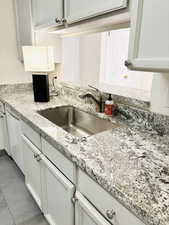 Kitchen with white cabinets, light stone countertops, and white dishwasher