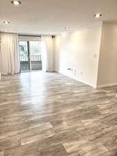 Empty room with wood finished floors, recessed lighting, and crown molding