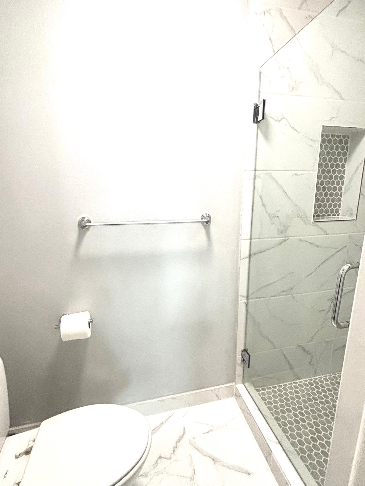 Bathroom featuring a marble finish shower and light marble finish flooring