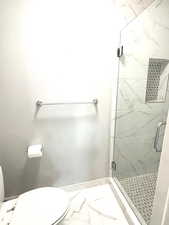 Bathroom featuring a marble finish shower and light marble finish flooring