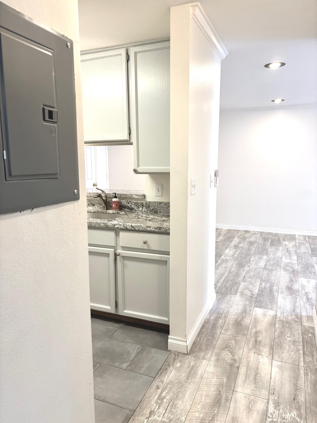 Kitchen featuring electric panel, light wood-style floors, and light stone counters