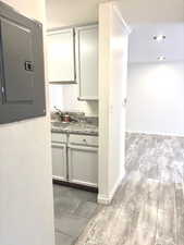 Kitchen featuring electric panel, light wood-style floors, and light stone counters