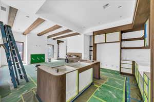 Kitchen featuring beam ceiling and white cabinetry