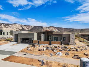 Modern home featuring a mountain view, driveway, an attached garage, stucco siding, and stone siding