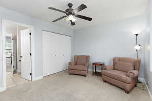 Sitting room featuring light carpet and ceiling fan