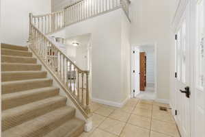 Stairway with a high ceiling and tile patterned flooring