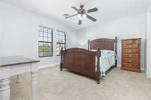 Bedroom with light colored carpet and a ceiling fan