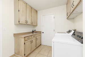 Laundry room with washer and dryer, cabinet space, and light tile patterned floors