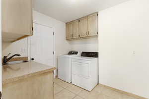 Laundry area featuring cabinet space, light tile patterned floors, and washer and dryer