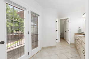 Bathroom with vanity, light tile patterned floors, and ornamental molding