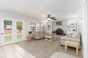 Living area featuring light tile patterned floors, ceiling fan, ornamental molding, light carpet, and built in shelves