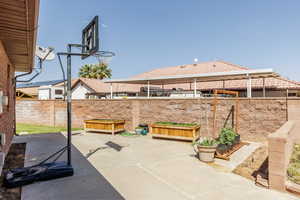 Fenced backyard featuring a patio area and a vegetable garden