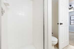 Full bathroom with ceiling fan, a shower stall, and light tile patterned floors