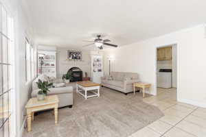 Living area with ornamental molding, light tile patterned floors, ceiling fan, and built in features
