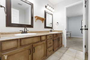 Full bathroom featuring double vanity, light colored carpet, and light tile patterned floors