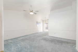 Carpeted spare room with a ceiling fan and vaulted ceiling