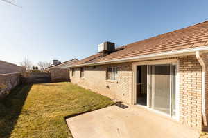 Rear view of house with brick siding, a fenced backyard, and a patio area