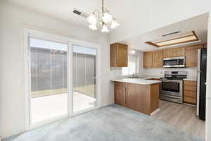Kitchen with light countertops, stainless steel appliances, wood finish cabinets, lofted ceiling, and hanging lights