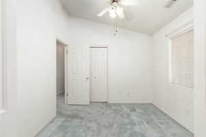 Unfurnished bedroom with lofted ceiling, light colored carpet, a ceiling fan, and a closet