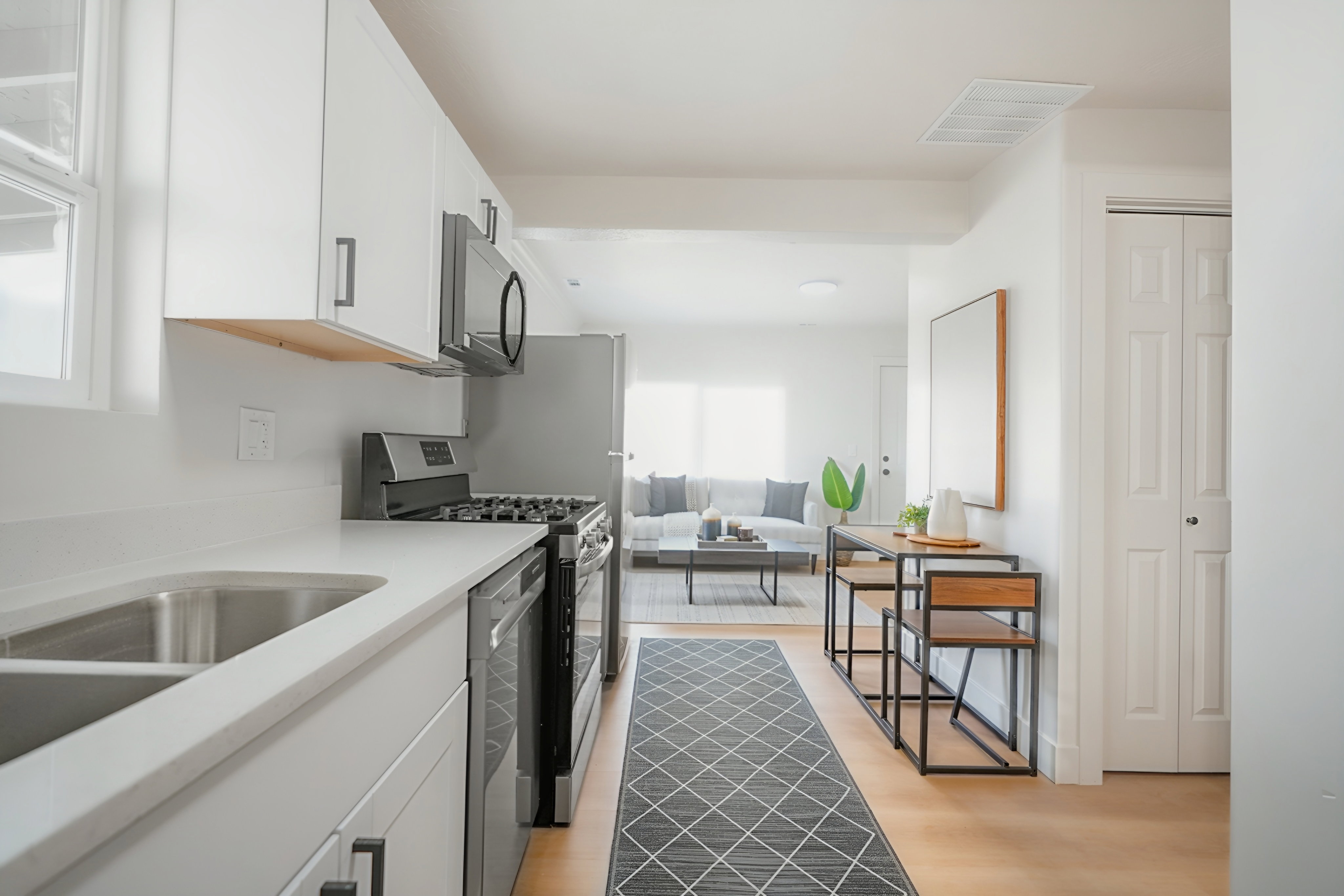 Kitchen featuring white cabinetry, stainless steel appliances, light wood-style floors, and light stone countertops