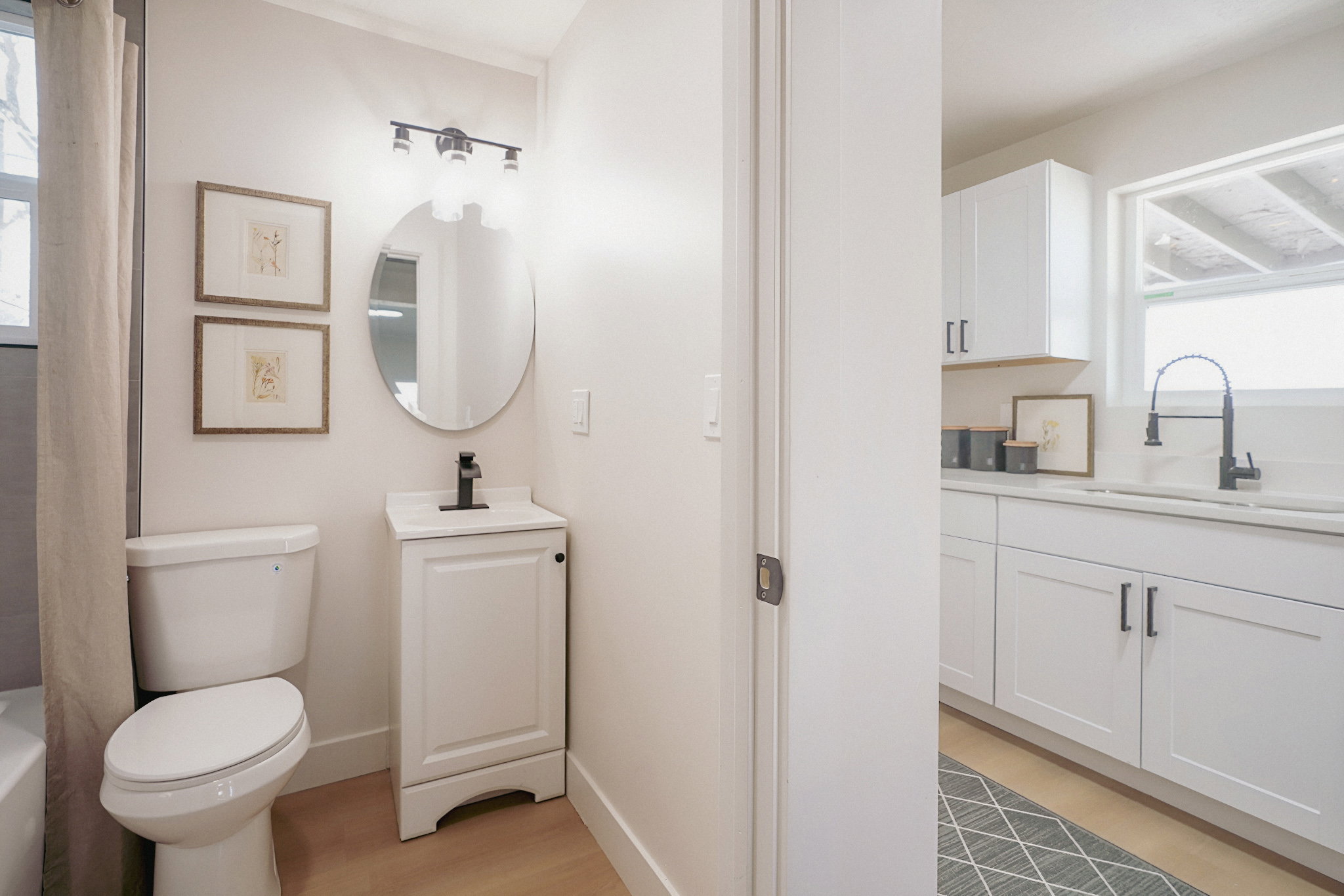 Bathroom featuring plenty of natural light, two vanities, light wood finished floors, and a bath