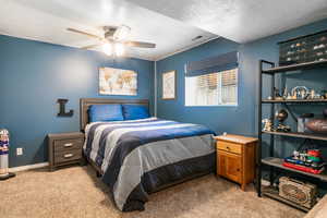 Bedroom with light carpet, a textured ceiling, and a ceiling fan