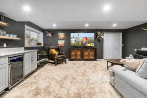 Carpeted living room with beverage cooler, a dry bar, and recessed lighting