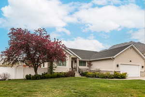 View of front of house featuring an attached garage, stucco siding, stone siding, and driveway