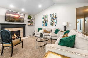 Carpeted living room with a fireplace and lofted ceiling