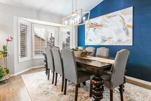 Dining space featuring vaulted ceiling, light wood finished floors, and suspended lighting