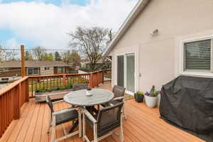 Wooden terrace with outdoor dining area, grilling area, and a residential view