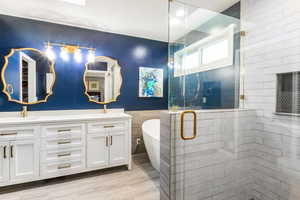 Bathroom featuring double vanity, a stall shower, a freestanding bath, and tile walls