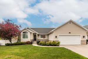 Single story home with stucco siding, a garage, stone siding, and concrete driveway