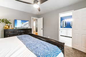 Bedroom featuring a ceiling fan, dark speckled floor, and connected bathroom