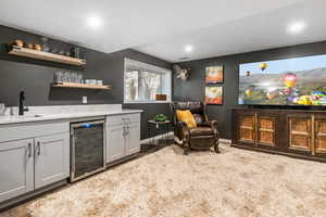 Indoor wet bar with open shelves, light stone counters, wine cooler, recessed lighting, and dark carpet