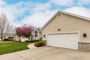 View of front of home with stucco siding, concrete driveway, a garage, and a front lawn