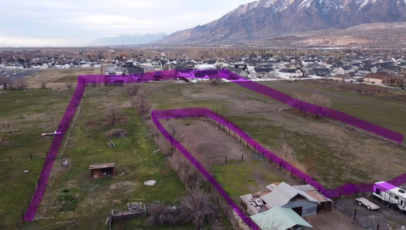 Aerial view of residential area featuring property boundaries highlighted and mountains