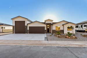 Ranch-style house with stone siding, an attached garage, stucco siding, and concrete driveway
