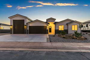 View of front of home with a garage, stone siding, concrete driveway, and stucco siding