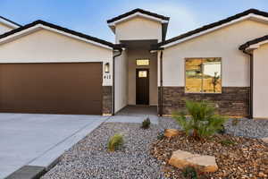Modern home featuring a garage, stucco siding, concrete driveway, and stone siding