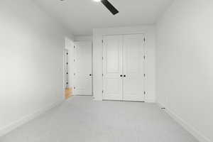 Unfurnished bedroom with light colored carpet, ceiling fan, and a closet