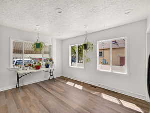Unfurnished dining area featuring light wood-type flooring, a textured ceiling, and recessed lighting