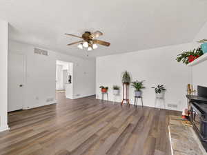 Living room featuring a ceiling fan, dark wood-style flooring, and a textured ceiling