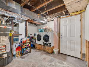 Unfinished below grade area featuring water heater and washer and clothes dryer