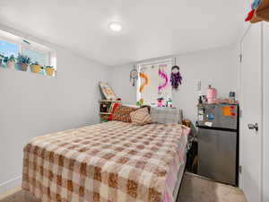 Carpeted bedroom with freestanding refrigerator