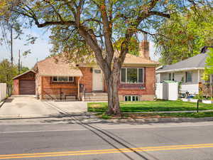View of front of home with a chimney, brick siding, a garage, concrete driveway, and roof with shingles