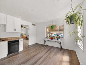 Kitchen featuring black dishwasher, white cabinets, light stone countertops, dark wood-type flooring, and recessed lighting