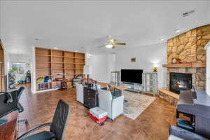Living area with a ceiling fan, a fireplace, tile patterned floors, and a desk