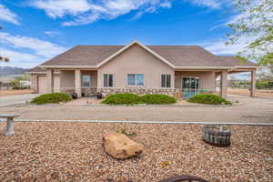 Single story home featuring stucco siding, roof with shingles, stone siding, and a porch