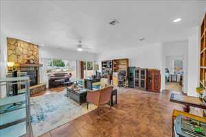 Living area featuring a stone fireplace, a textured ceiling, ceiling fan, recessed lighting, and an office area